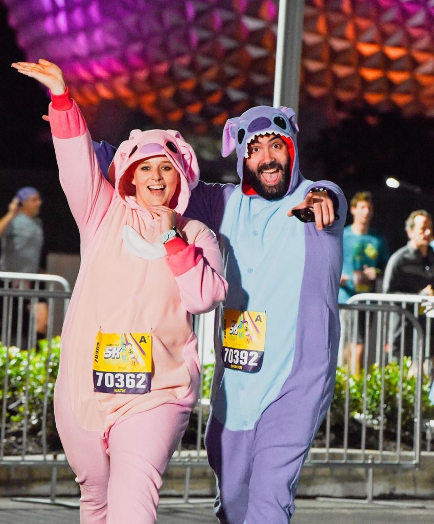 Katie and Spencer running in Lilo and Stitch costumes in front of Spaceship Earth during 2020 Walt Disney World 5K