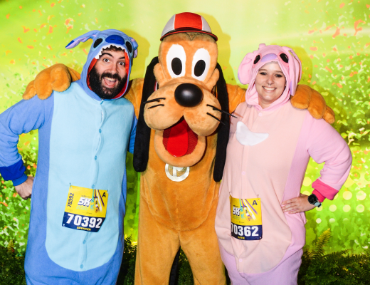 Katie and Spencer dressed in Lilo and Stitch onesies with Pluto the Dog at Walt Disney World 5K