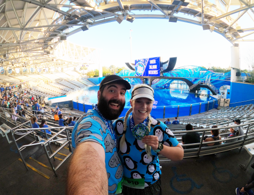Katie and Spencer holding their Sea World Rescue Run medals in Shamu Stadium