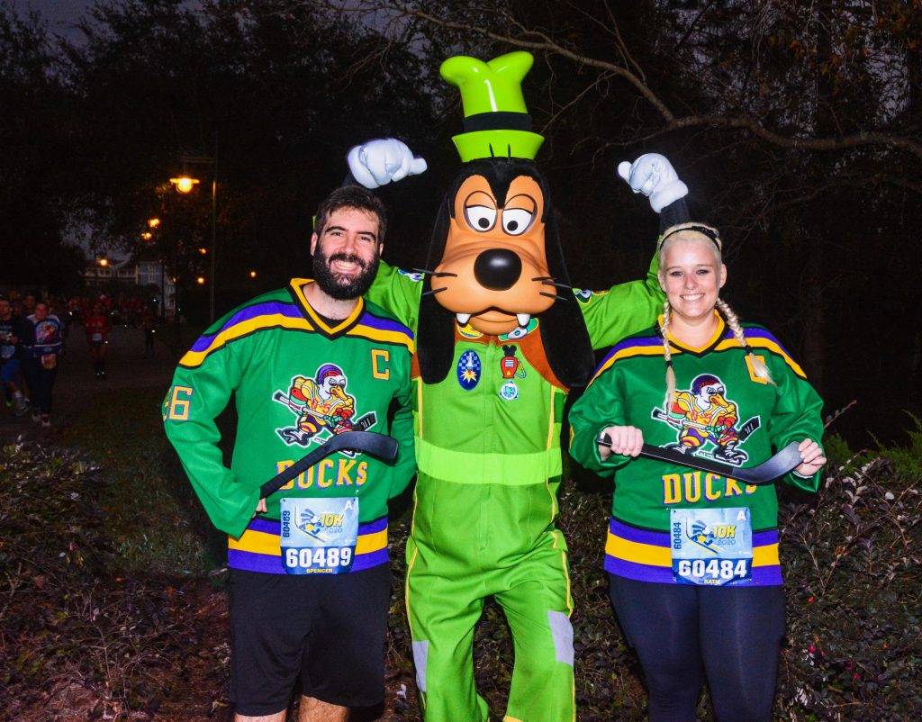 Katie and Spencer wearing Mighty Ducks jerseys during 2020 Walt Disney World 10K with Goofy wearing Roadster costume